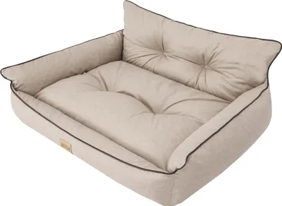 A beige dog bed with brown trim and tufted cushions.