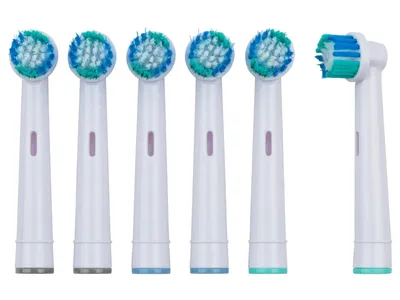 A set of six replacement toothbrush heads arranged in a row, with one head detached and angled.