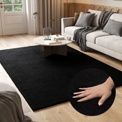 A living room scene with a black rug, a white sofa, and a coffee table.