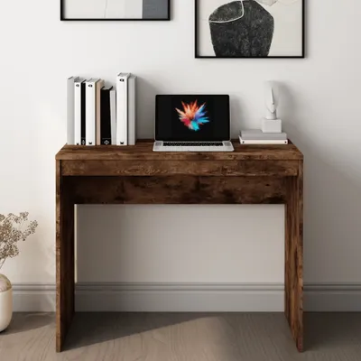 A desk with a laptop and books on it, placed against a wall.
