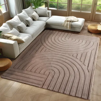 A modern living room with a large sectional sofa and a patterned rug.