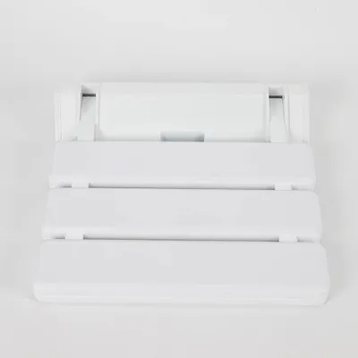 A white foldable shower seat mounted on a white wall.
