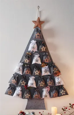 A felt advent calendar shaped like a Christmas tree, hanging on a wall.