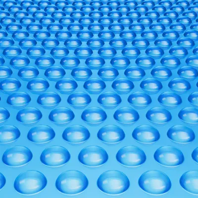 A close-up, angled view of a blue solar pool cover with a repeating pattern of raised bubbles.