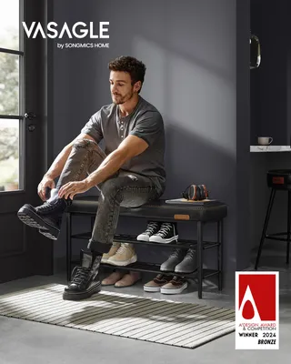 A man is sitting on a shoe bench and putting on his boots in an entryway.