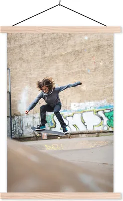 Produktbild von MuchoWow® Textilposter Ein Mädchen macht einen Stunt mit ihrem Skateboard 40x60 cm mit holzfarbenen Rahmen - Poster
