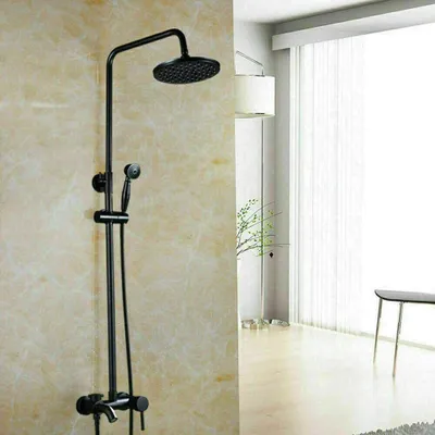A black shower system is mounted on a textured wall, with a bright window and a plant in the background.
