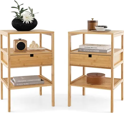 Two identical bamboo nightstands are shown against a white background. Each nightstand has a drawer and two shelves. The left nightstand has a decorative vase with flowers, a small speaker, and some decorative items on its shelves. The right nightstand has