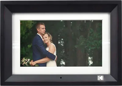 A digital photo frame displaying a wedding photo of a couple embracing outdoors.