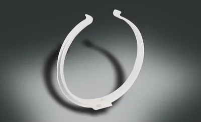 A white circular object with open ends is shown against a gradient gray background.