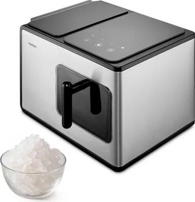 A silver and black ice maker with a clear bowl of ice in front of it, on a white background.