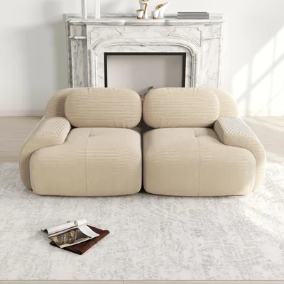 A beige loveseat sofa is placed on a patterned rug in front of a marble fireplace.