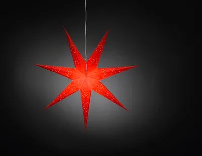 A red paper star lantern with white speckles hangs against a dark, gradient background.