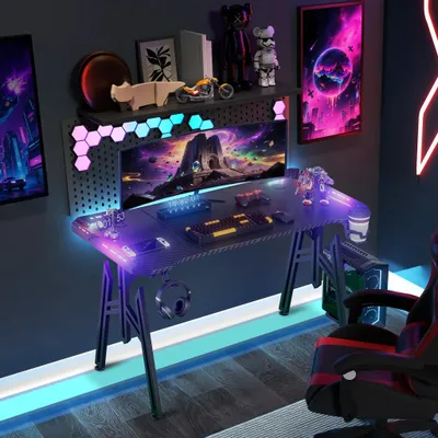 A gaming desk setup with a computer, keyboard, mouse, and chair, illuminated by RGB lighting.
