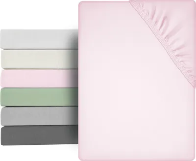 A stack of folded fitted sheets in various colors next to a single pink fitted sheet.