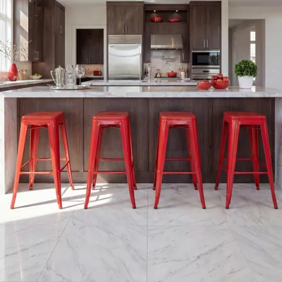 A modern kitchen with dark wood cabinets, a stainless steel refrigerator, and a marble countertop. Four red bar stools are arranged in front of the counter.