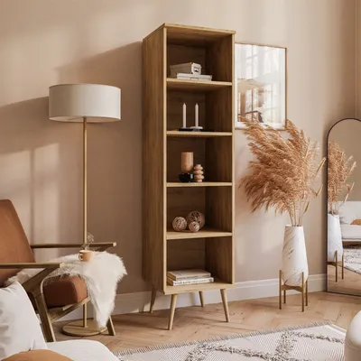 A tall wooden bookshelf filled with decorative items, placed in a living room setting next to a chair and a floor lamp.