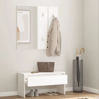 A minimalist hallway entryway setup featuring a white shoe bench with a drawer, a mirror, a coat rack with a beige jacket, a tote bag, and an umbrella stand with umbrellas.
