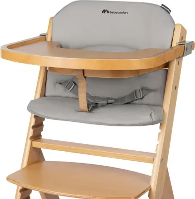 A close-up view of a baby high chair with a gray cushion and a wooden tray.