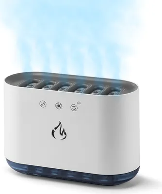 A white humidifier with a blue base is shown from a slightly elevated front-left angle, emitting a blue mist from its top. It has several small icons and a flame logo on its front.