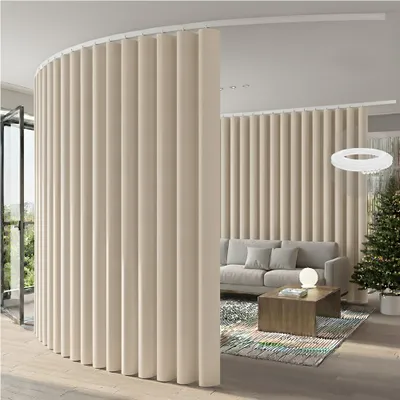 A curved room divider made of beige fabric panels separates a living area with a sofa and coffee table from another space, possibly a hallway or entrance, with a Christmas tree visible in the background.