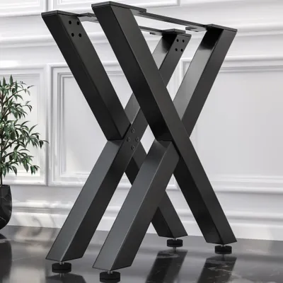 A black metal table base with an X-shaped design, shown in a room with white walls and a dark floor.