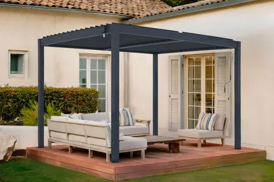 An outdoor patio area with a modern pergola, seating, and a coffee table.