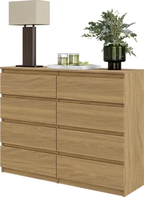 A wooden dresser with eight drawers, a lamp, and decorative items on top, set against a white background.