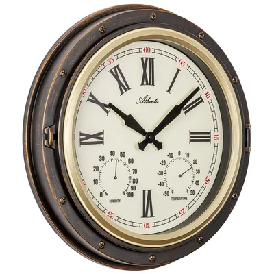 A close-up, angled view of a round wall clock with Roman numerals and two smaller dials for humidity and temperature.
