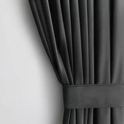 A close-up view of a dark gray curtain with pleats and a fabric band.