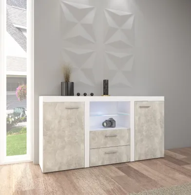 A modern sideboard with a concrete-look finish and white accents, placed in a living room setting with a window and textured wall.