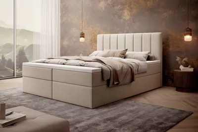 A bedroom scene featuring a large bed with bedding, a headboard, and a bedside table with decor. Large windows with a scenic view are visible in the background.