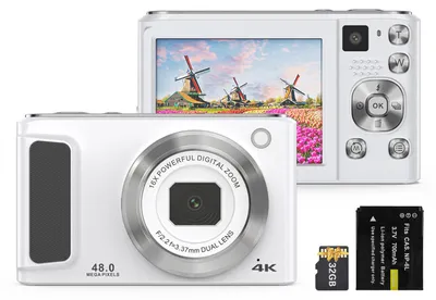 A white digital camera is shown with its accessories, a battery and an SD card, placed next to it. The camera's screen displays a scenic image of windmills and flowers.