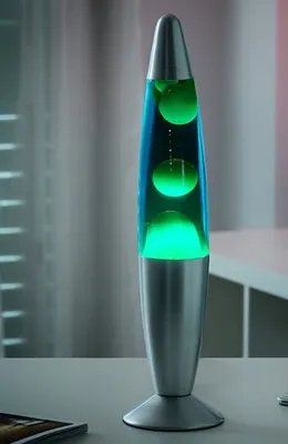 A lava lamp with green blobs in blue liquid sits on a desk.