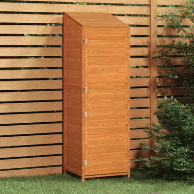 A tall, narrow wooden storage shed stands on a grassy lawn in front of a slatted wooden fence.