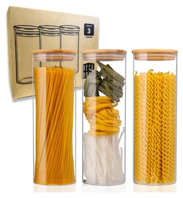 Three glass jars filled with different types of pasta, with a cardboard box in the background.