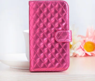 A pink quilted metallic phone case is displayed on a white surface with blurred flowers in the background.