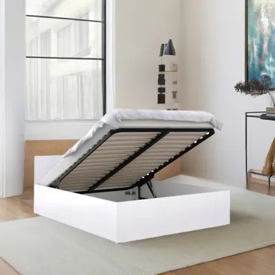 A white bed frame with the mattress lifted, revealing storage space underneath, in a bedroom setting.