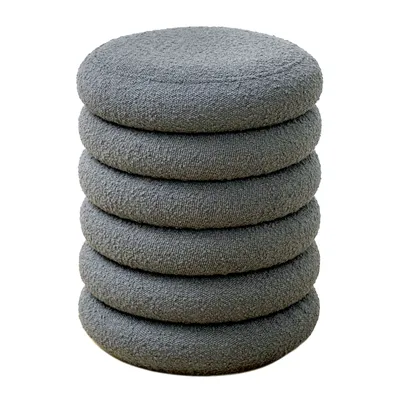 A stack of six round, grey, boucle-upholstered ottomans or stools.