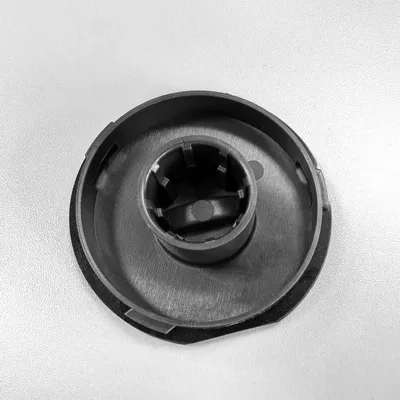 A close-up, top-down view of a black plastic component with a central cylindrical hub with internal grooves.