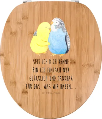 A wooden toilet seat lid with a drawing of two budgies and a German quote.