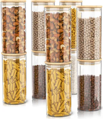 A collection of glass storage jars filled with different food items, arranged in a studio setting.