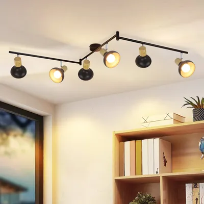 A ceiling light fixture with multiple adjustable spotlights is mounted on a white ceiling above a bookshelf.