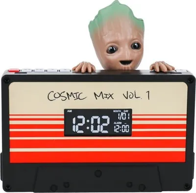 A Groot figure is peeking over a cassette tape-shaped alarm clock.