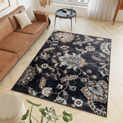 A living room scene with a brown leather sofa and a dark floral rug.