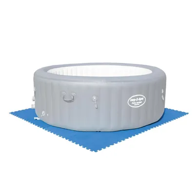 An inflatable hot tub sits on interlocking blue floor mats.
