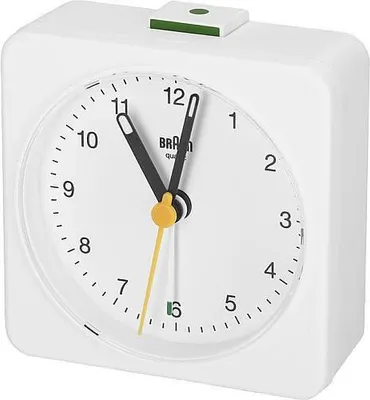 A white analog alarm clock with black hands and a yellow second hand.
