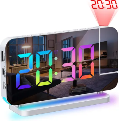 A digital alarm clock with a mirrored surface displaying the time and reflecting a living room scene. A red projection of the time is visible on the ceiling.