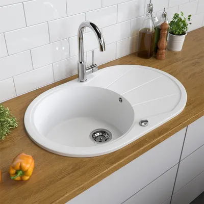 A white kitchen sink with a chrome faucet and a wooden countertop.