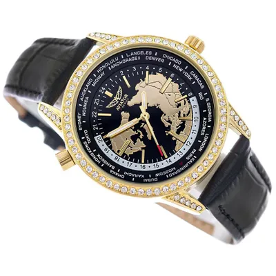 A close-up, angled view of a gold and black watch with a world map design on the face, set against a white background.